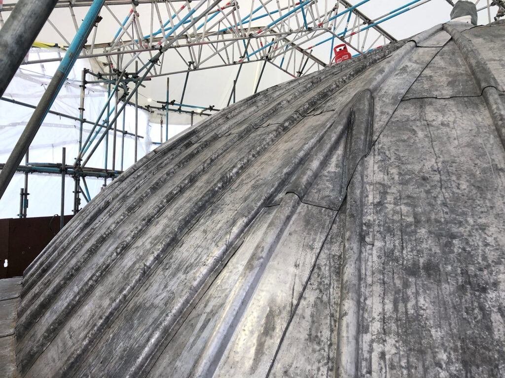 A domed roof with new lead applied beneath a temporary roof scaffold structure