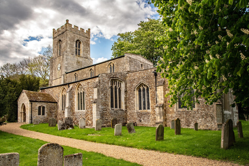 A view of a village church surrounded by gravestones on a cloudy day