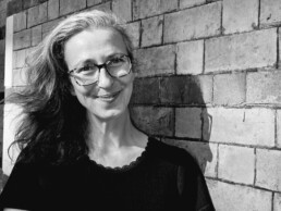 Black and white photograph of Anne smiling next to a brick wall